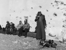مجموعة شيوخ يشربون الشاي في مكان مليء بالشظايا وآثار الرصاص في إحدى بلدات سهل نينوى المسيحية