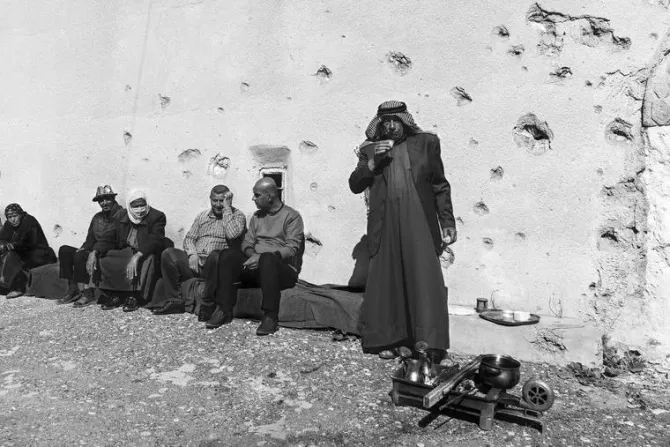 مجموعة شيوخ يشربون الشاي في مكان مليء بالشظايا وآثار الرصاص في إحدى بلدات سهل نينوى المسيحية