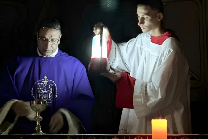 الأب يوسف أسعد يحتفل بالذبيحة الإلهيّة في رعيّة العائلة المقدّسة-غزّة على ضوء مصباح كهربائيّ
