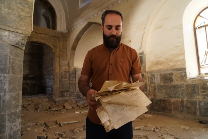 أحد المصلّين وهو ينفض الغبار عن كتب تُستخدم للصلوات داخل الكنيسة