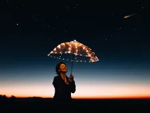 امرأة سعيدة تحمل مظلّة مزيّنة بالأضواء