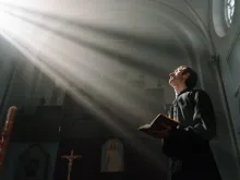 صورة تمثّل كاهنًا يصلّي في الكنيسة